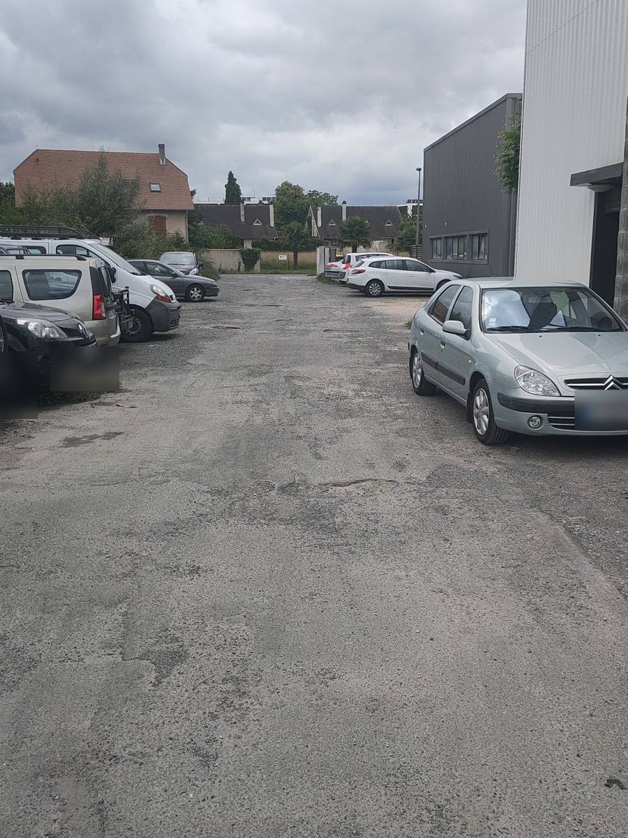 La cour devant les bâtiments, des voitures garées